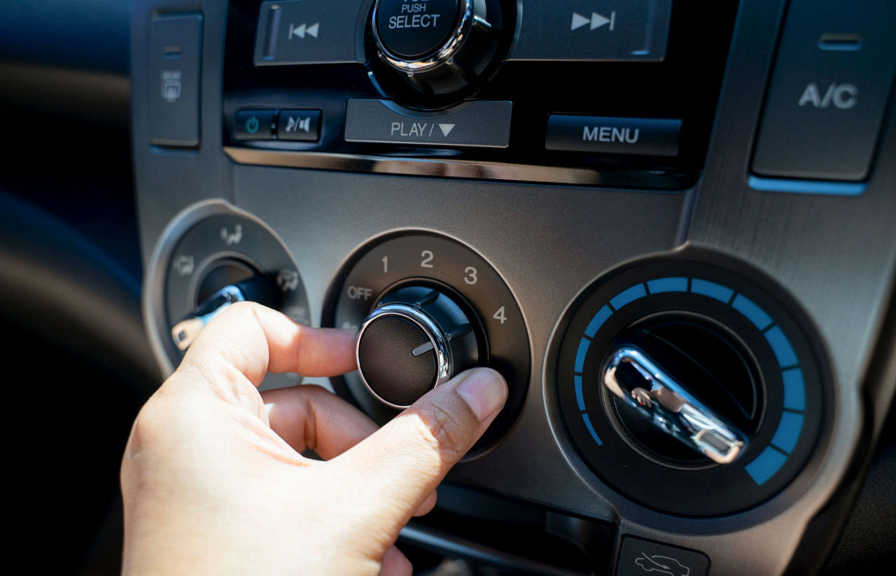 Close up view of a person adjusting the air conditioning in their car.