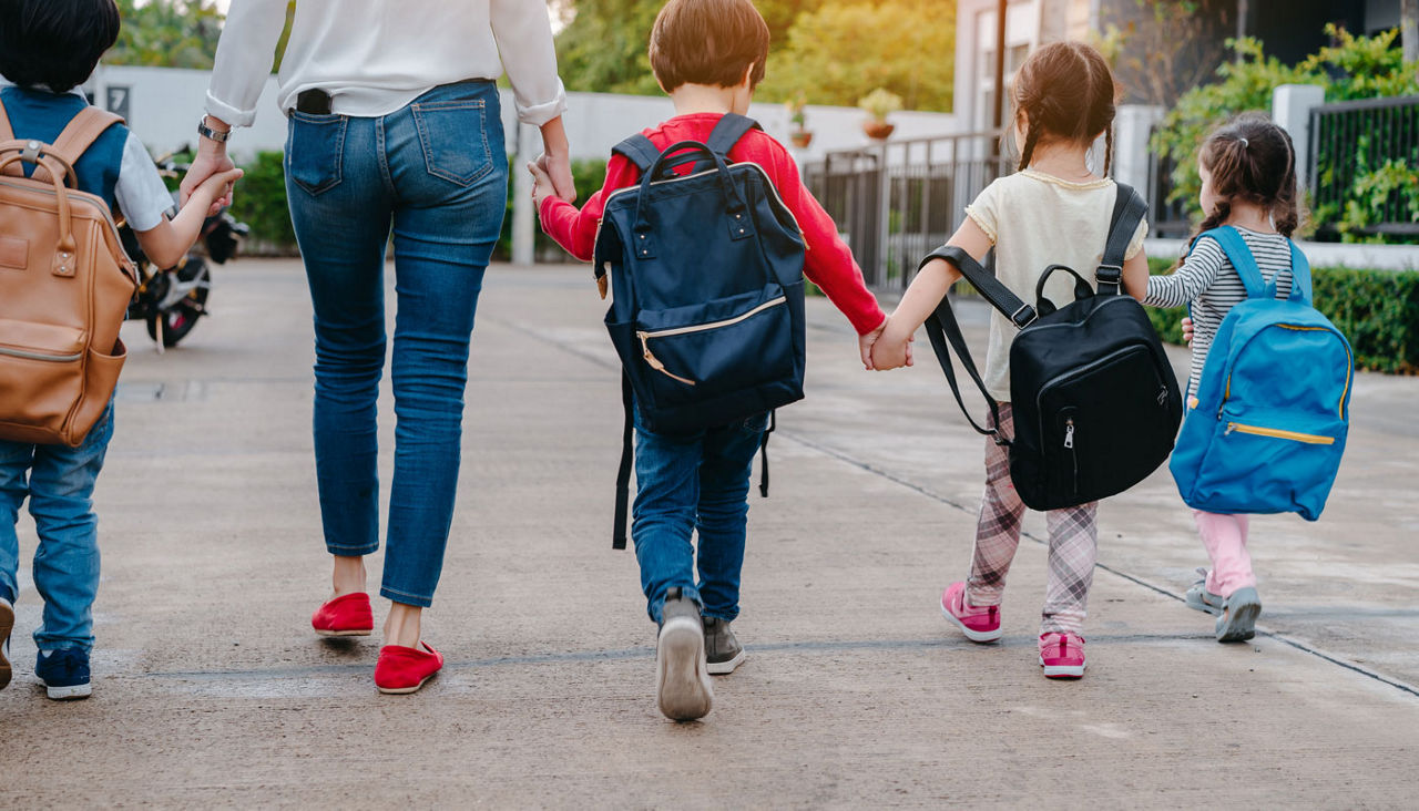Back to School of Mother and pupil and kids holding hands going to school