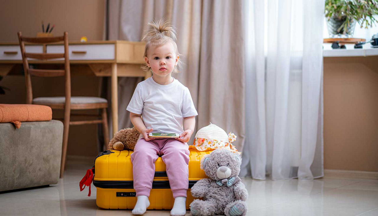 Little baby girl sitting on yellow suitcase baggage luggage, family ready to go for traveling on vacation at home