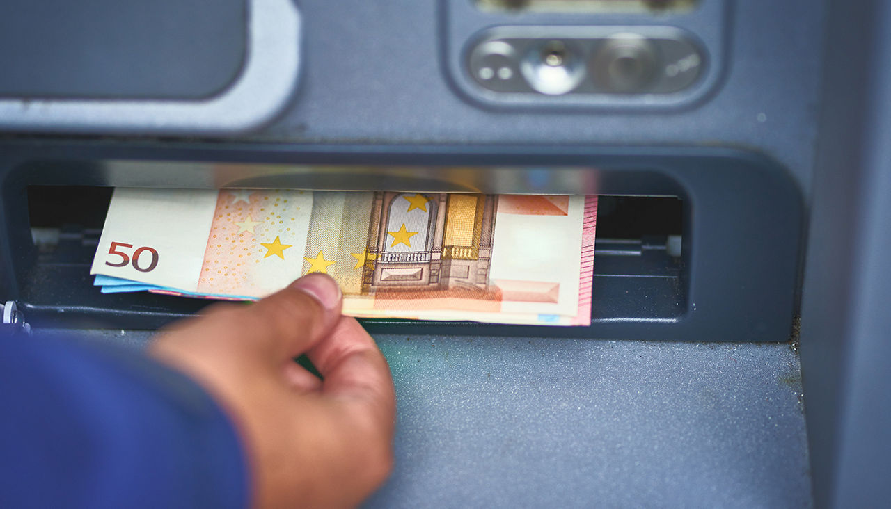 Closeup of hand withdrawing money from ATM