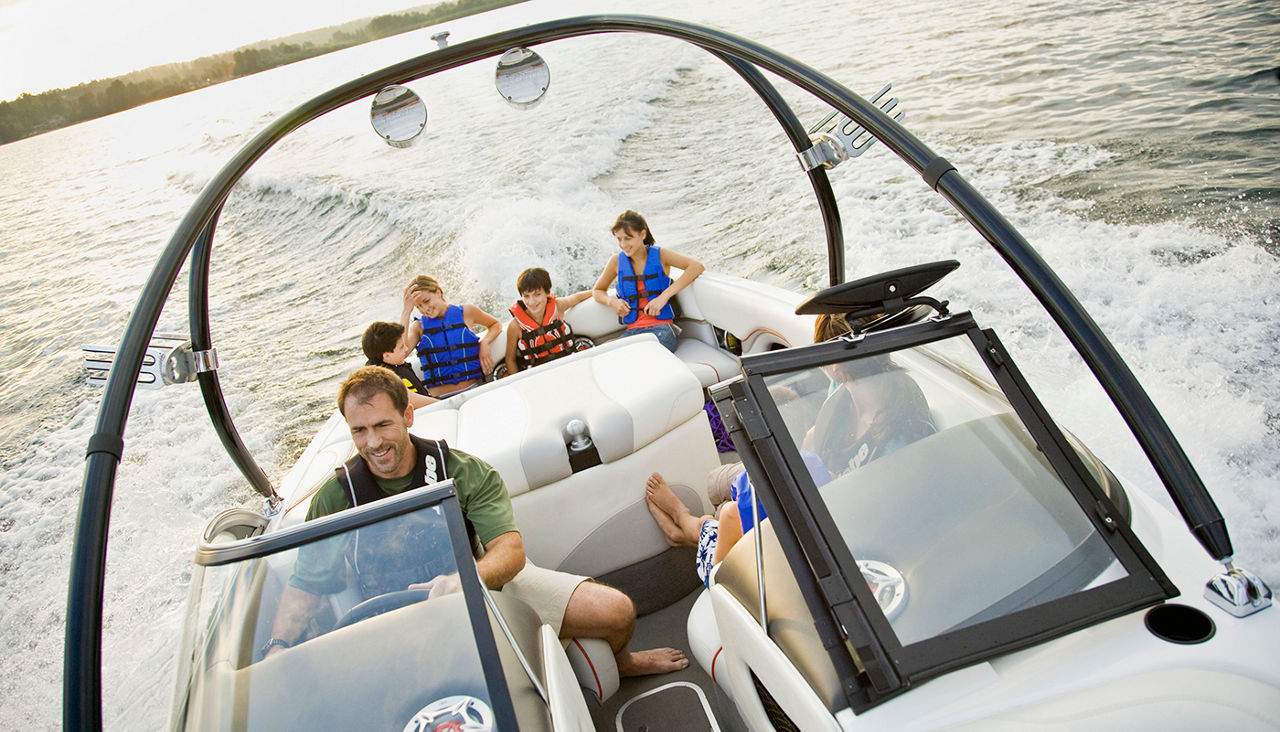 Family enjoying a boat ride on a lake with the sun setting in the background.