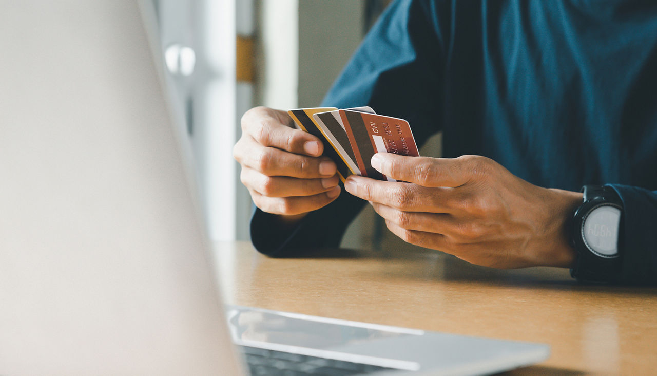 Man hand holding credit card and using laptop at home, Businessman or entrepreneur working, Online shopping, e-commerce, internet banking, spending money concept.