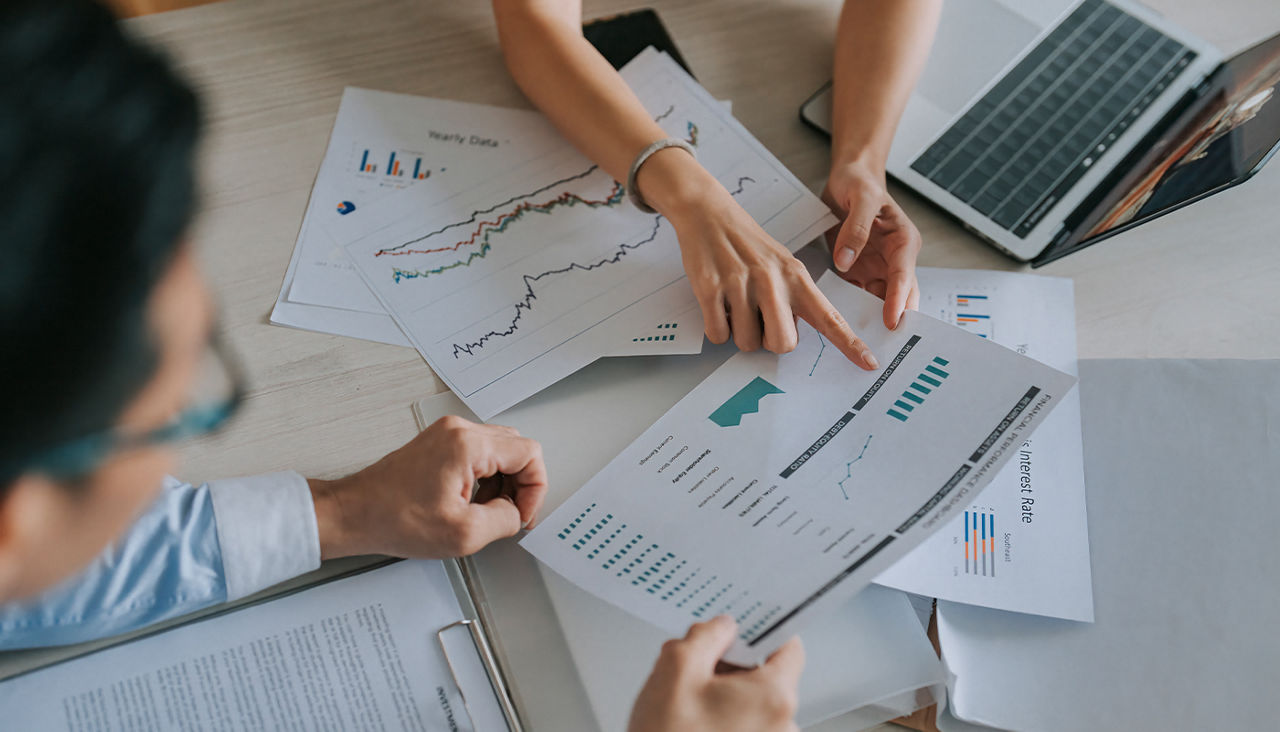 Two people examine invesment charts at a table. 