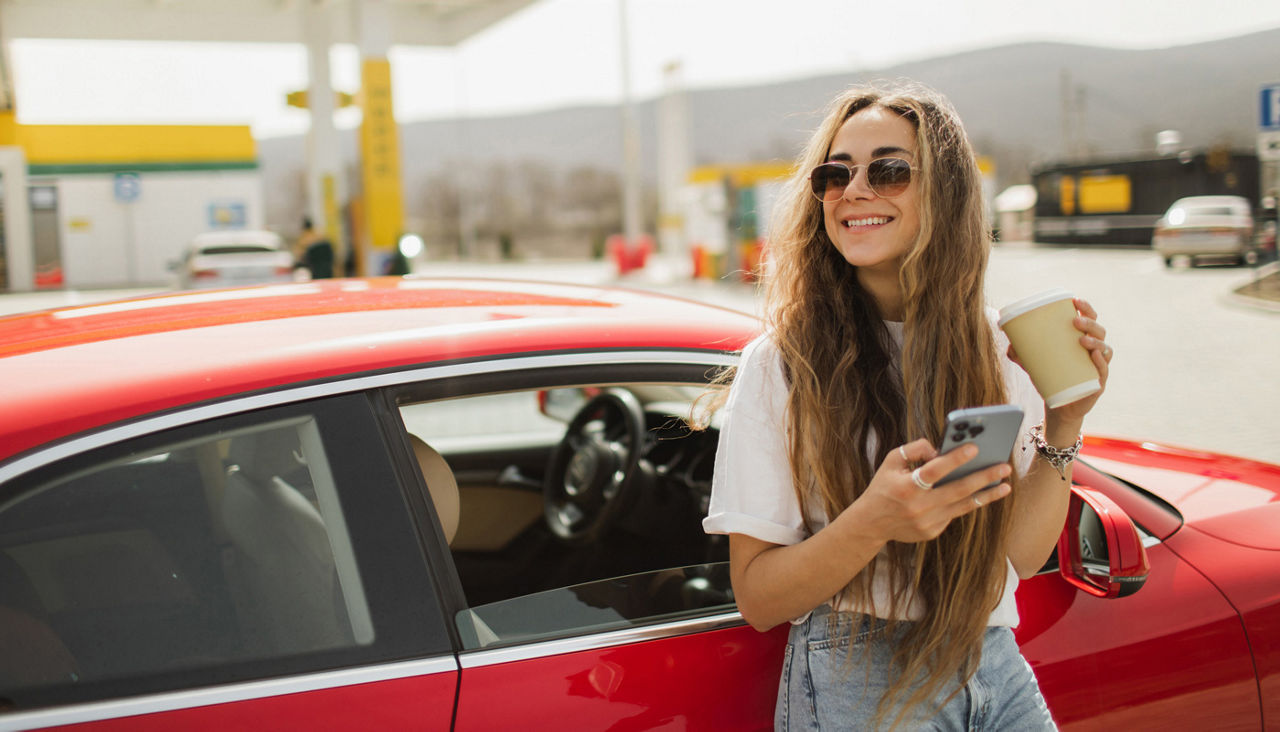Woman taking a break with coffee and mobile phone after driving
