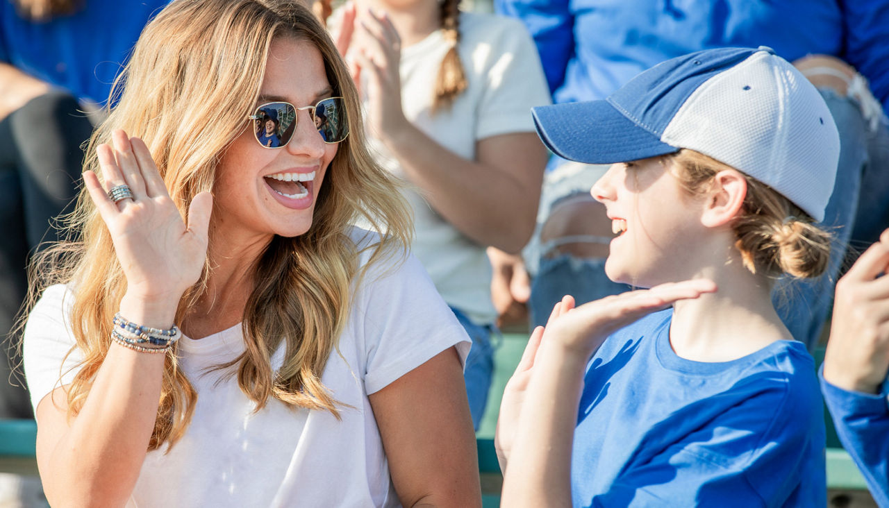 Woman and her daughter high five after team scores a touchdown at college football game
