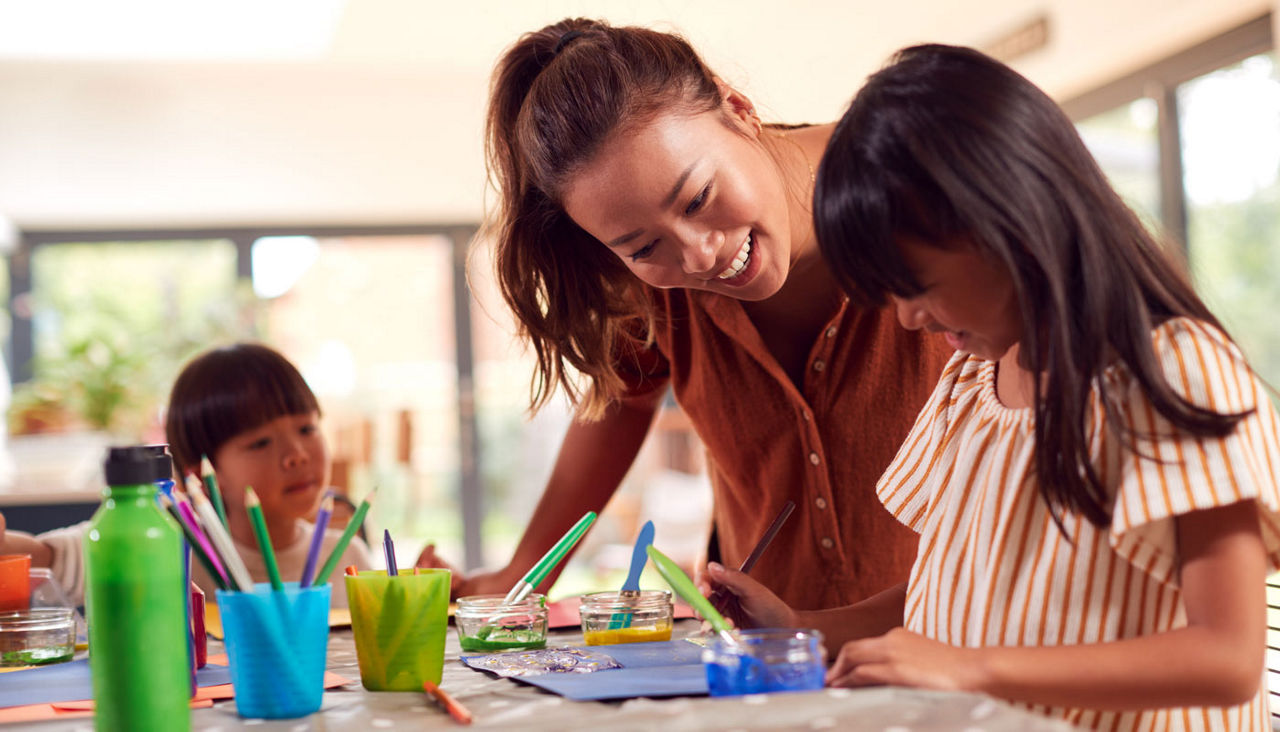 Asian Mother With Children Having Fun With Children Doing Craft On Table At Home