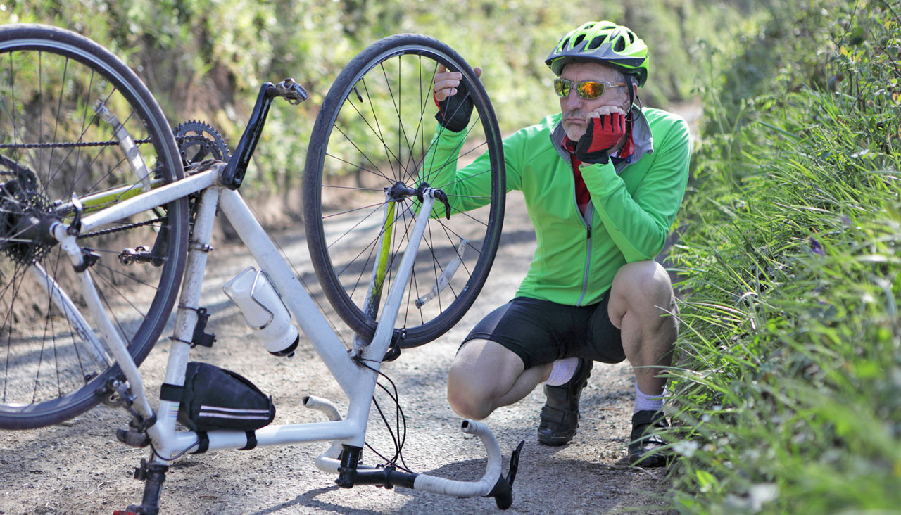 Man looking at bicycle with damaged wheel