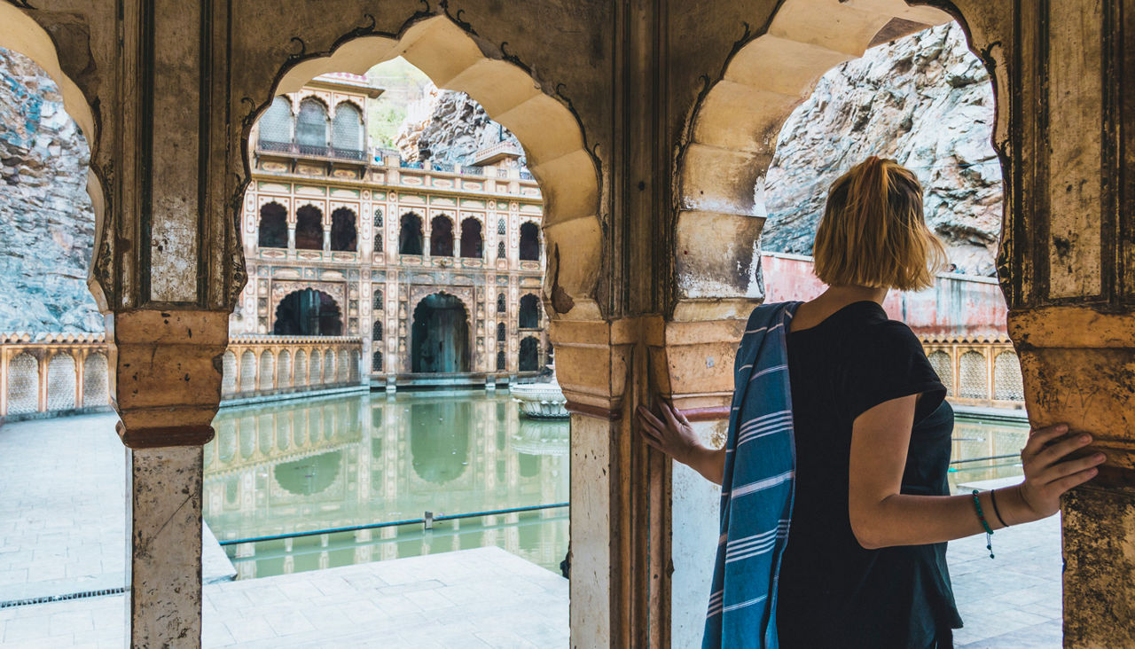 Young woman peers out from archway to lake