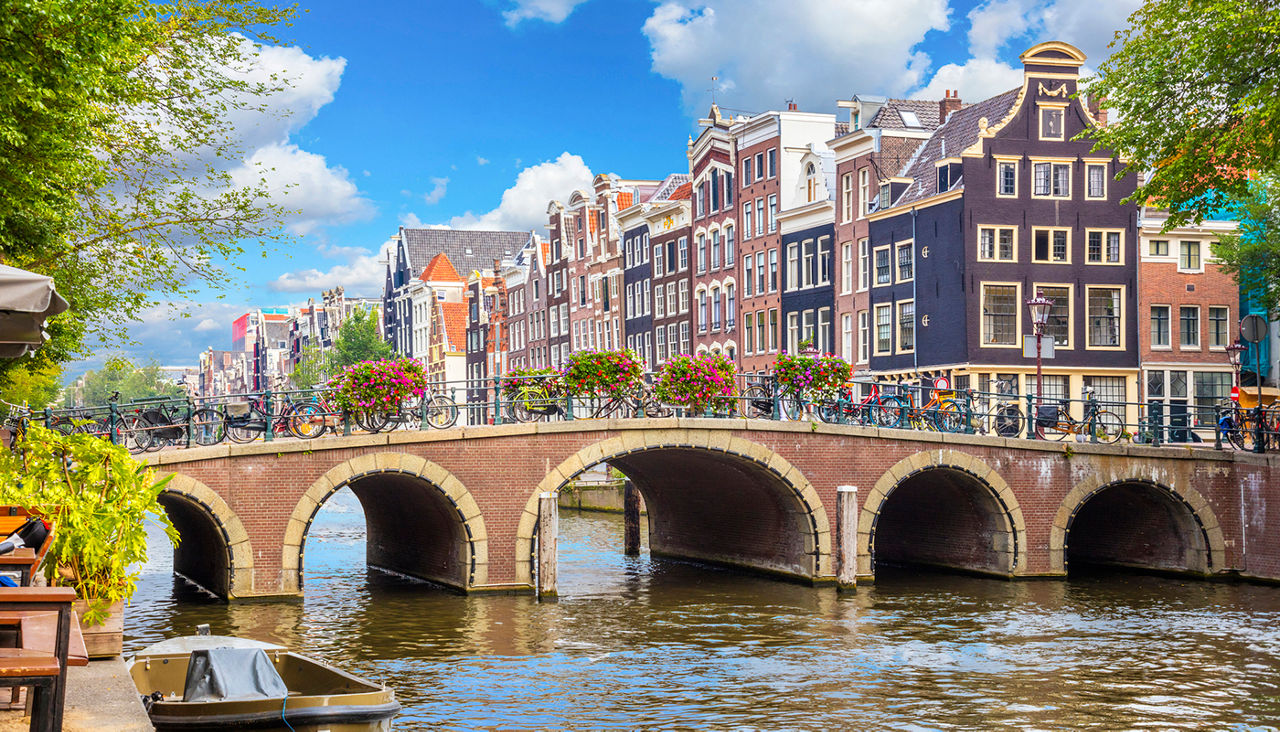 Amsterdam downtown - Amstel river, old houses and a bridge. Nice view of the famous city of Amsterdam. Travel to Europe. Amsterdam, Holland, Netherlands, Europe.