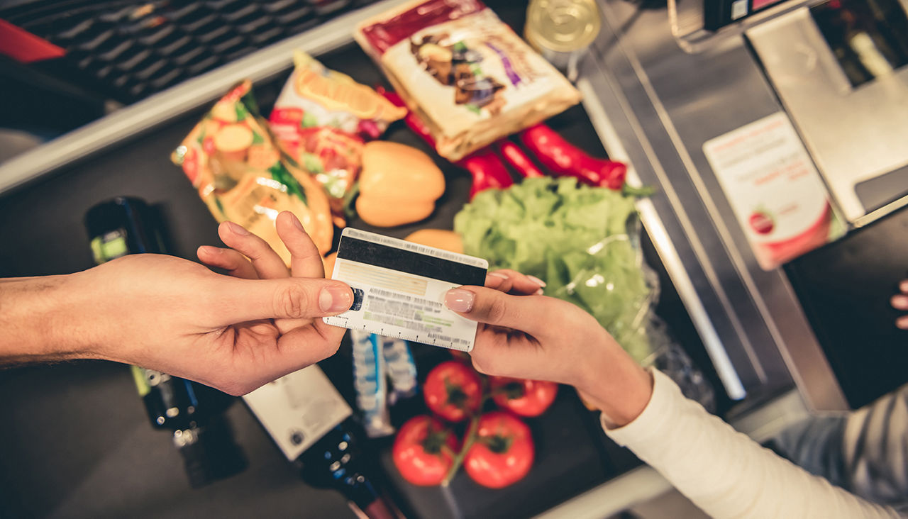 Cropped image of handsome man giving a credit card at the cash desk in the supermarket