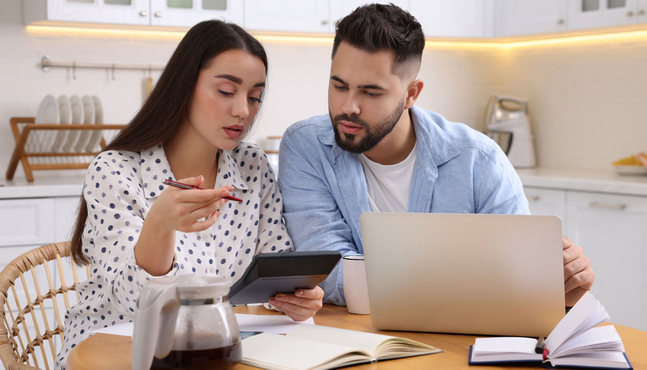 Young couple discussing family budget in kitchen