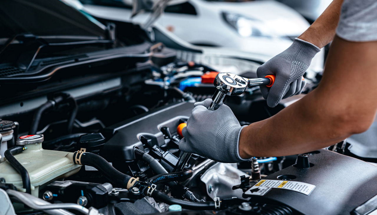 A mechanic using a socket wrench to tighten a bolt in a car engine.