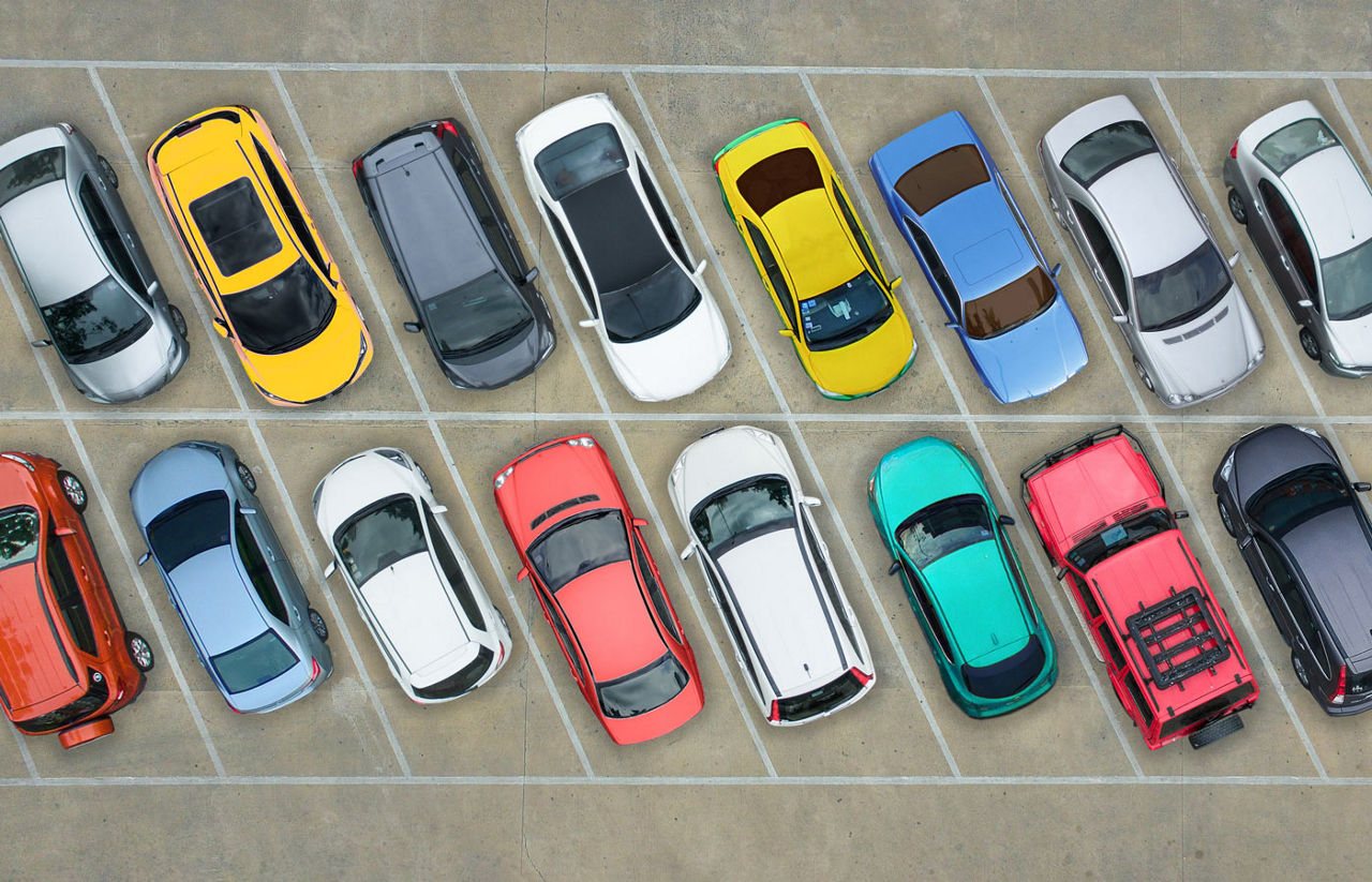 Rows of different color cars in a parking lot.