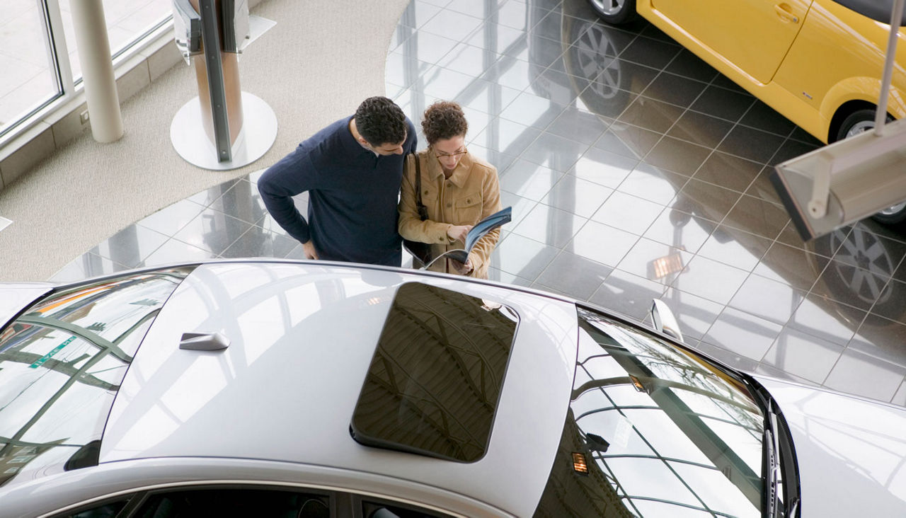 Couple reviewing new car brochure in showroom