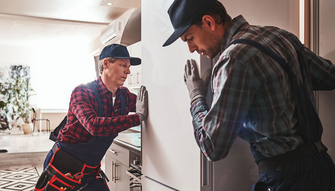 Young men mechanics checking refrigerator