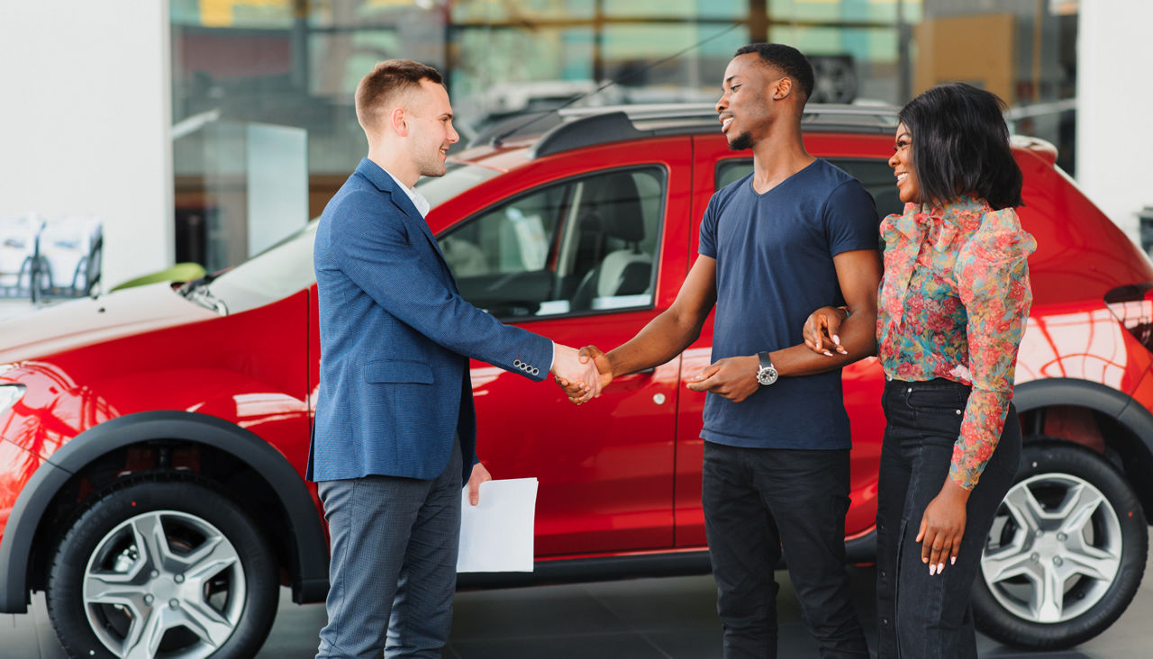 young african couple buying new car at dealership