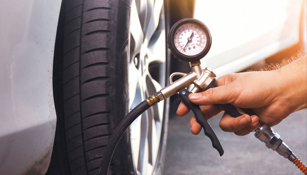 Close up view of a car tire being inflated by a tire pump.