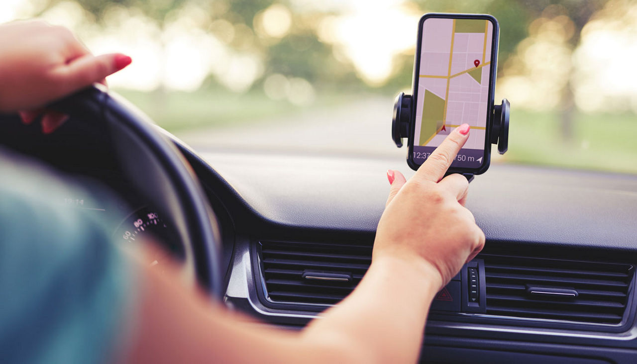 Female driver uses navigation on his mobile phone in the car