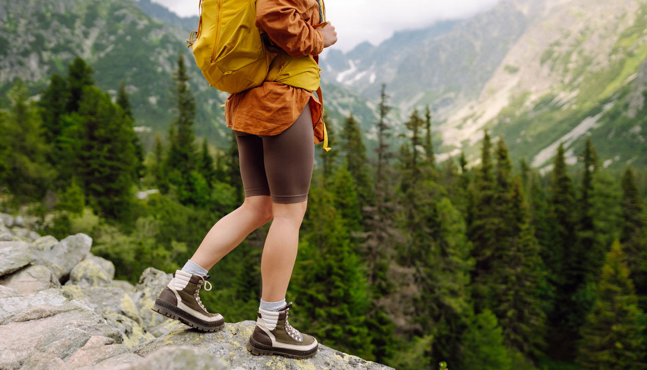 Close-up of female legs in hiking boots on a hiking trail, on top of a mountain outdoors. 