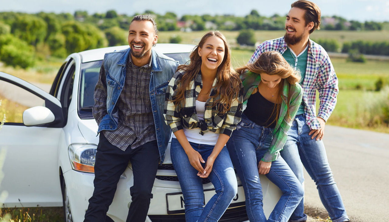 Group of people standing next travel in the car on road.