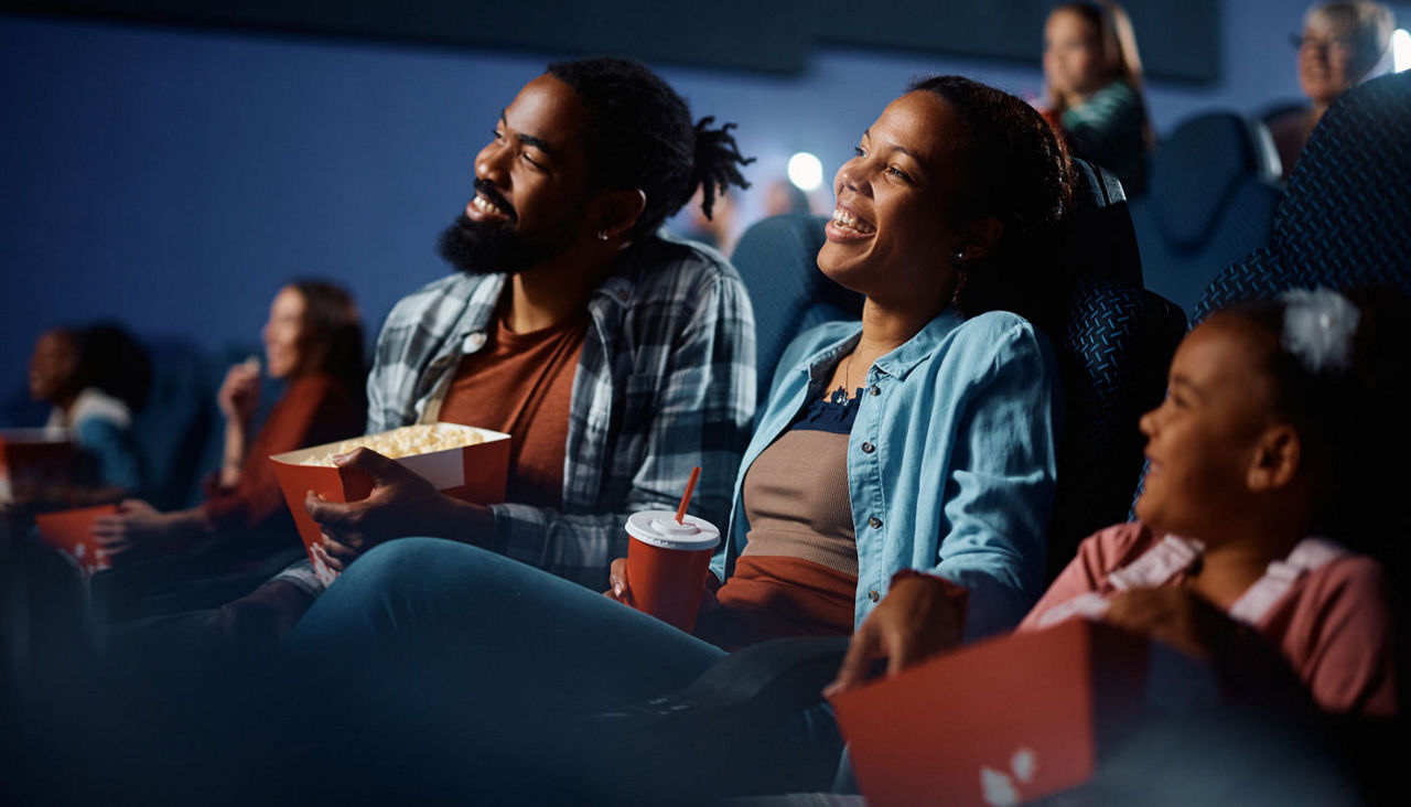 Happy black family enjoying in watching movie in cinema.