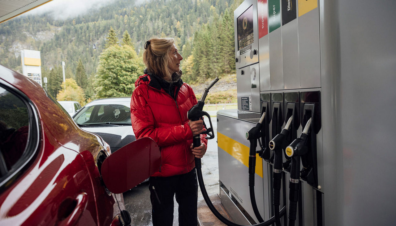 Picture of a woman in a winter coat pumping gas.