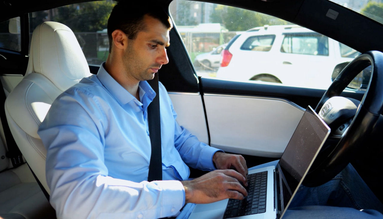 Business man working on notebook while riding an autonomous self driving electric car