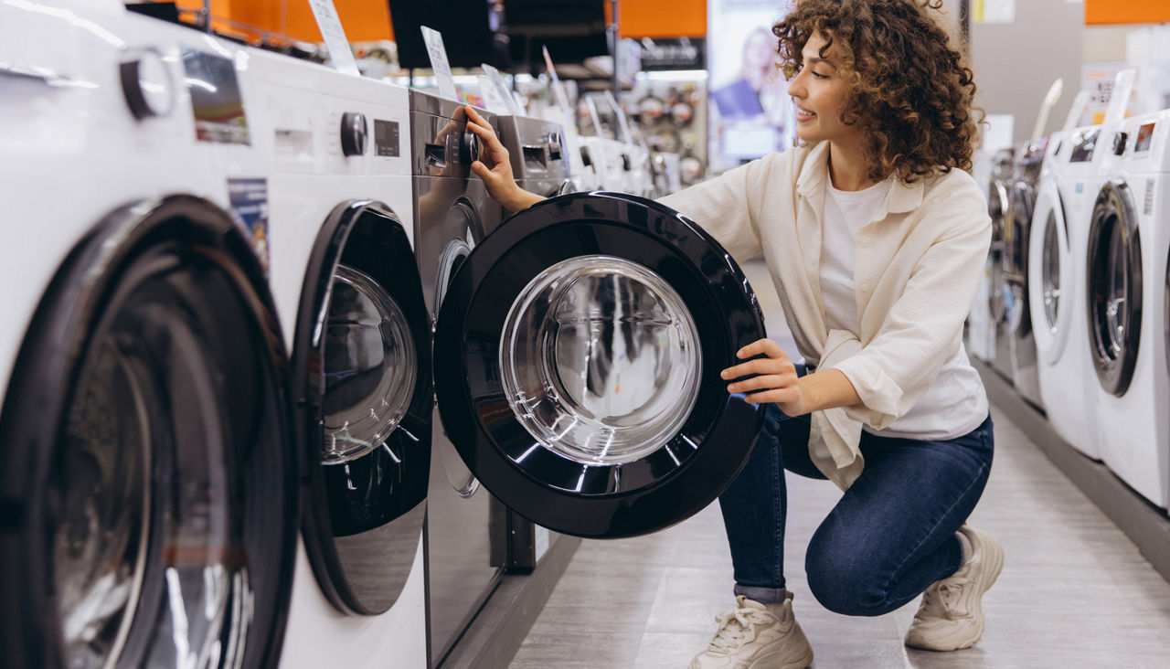 Woman Choosing Washing Machine in Appliance Store 
