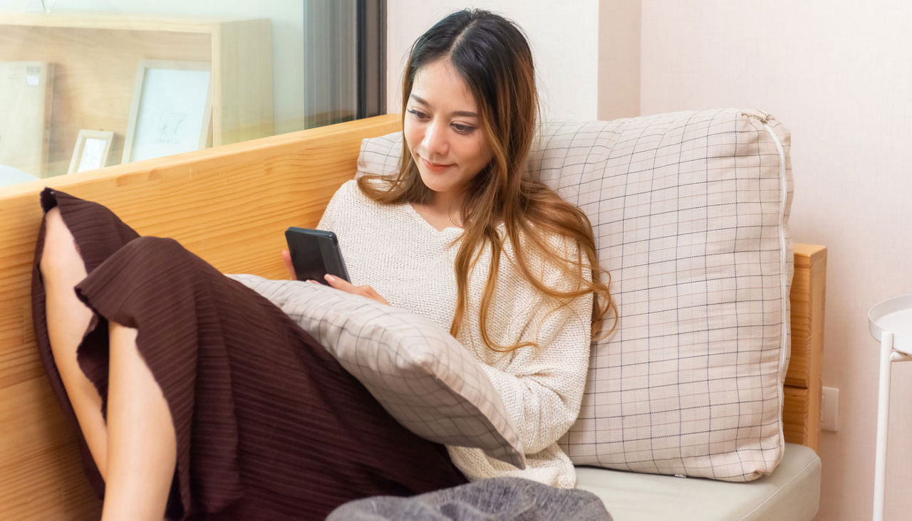 Woman on sofa using mobile phone for online shopping