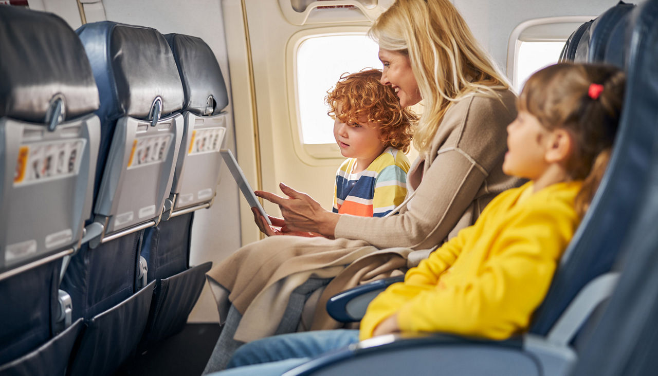 Woman inside a plane showing a tablet to a boy