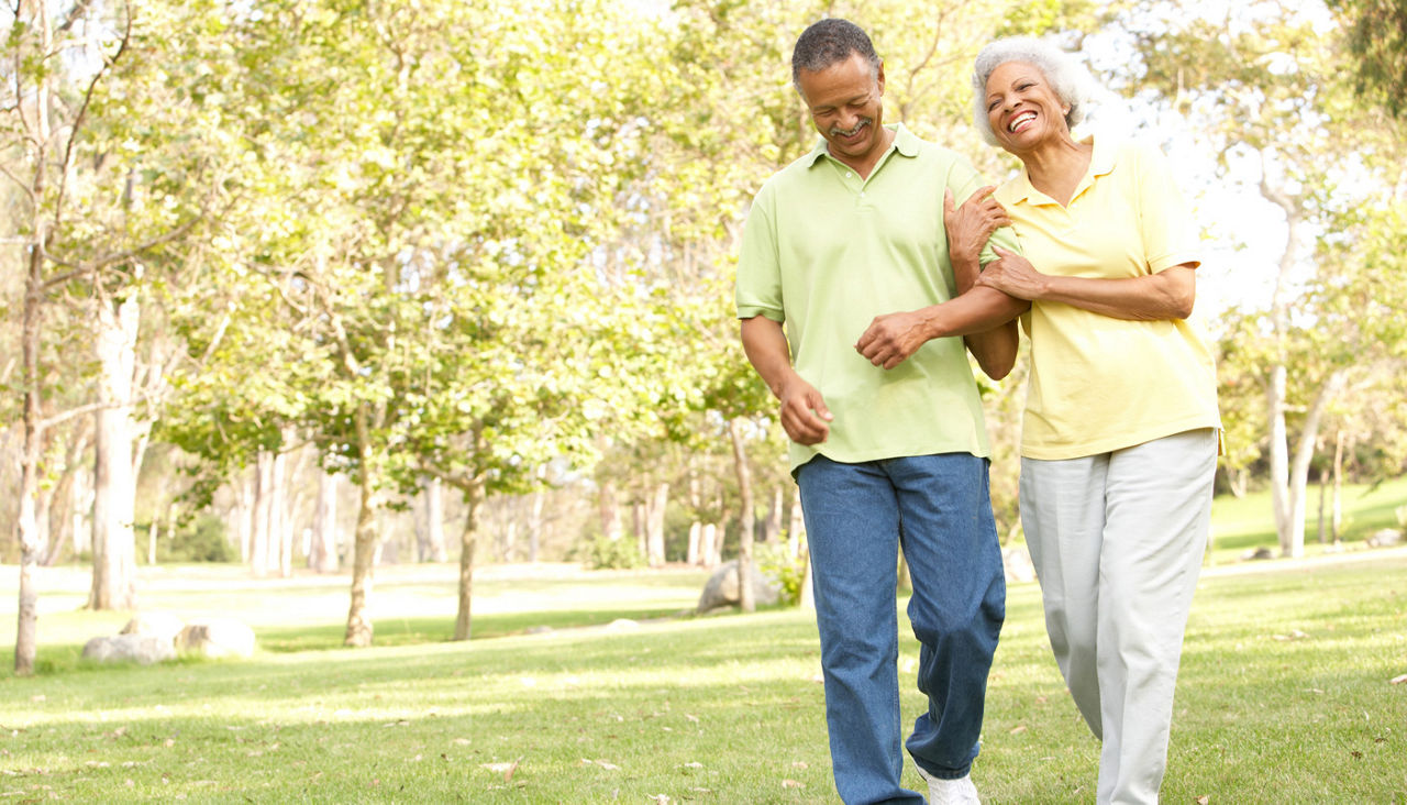 Senior couple walking arm in arm in park and laughing