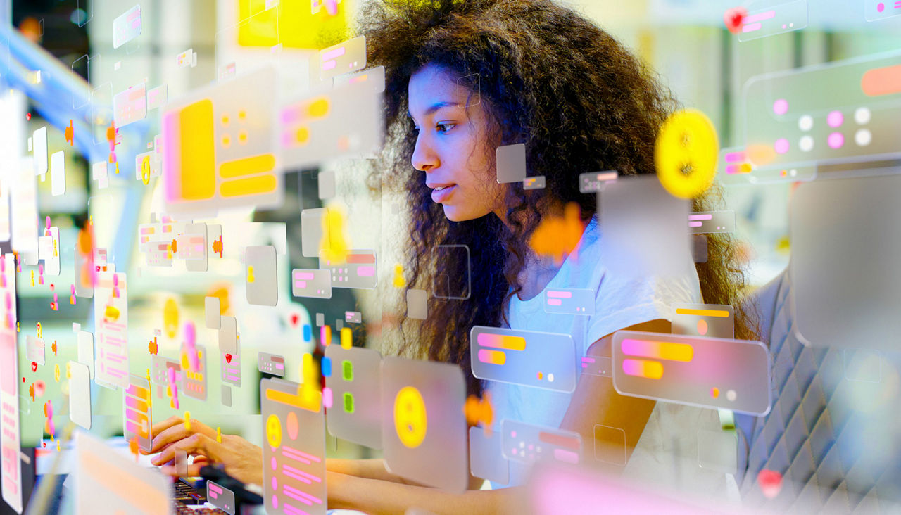 Portrait of young woman working in modern office surrounded by multicoloured social media icons and data screens