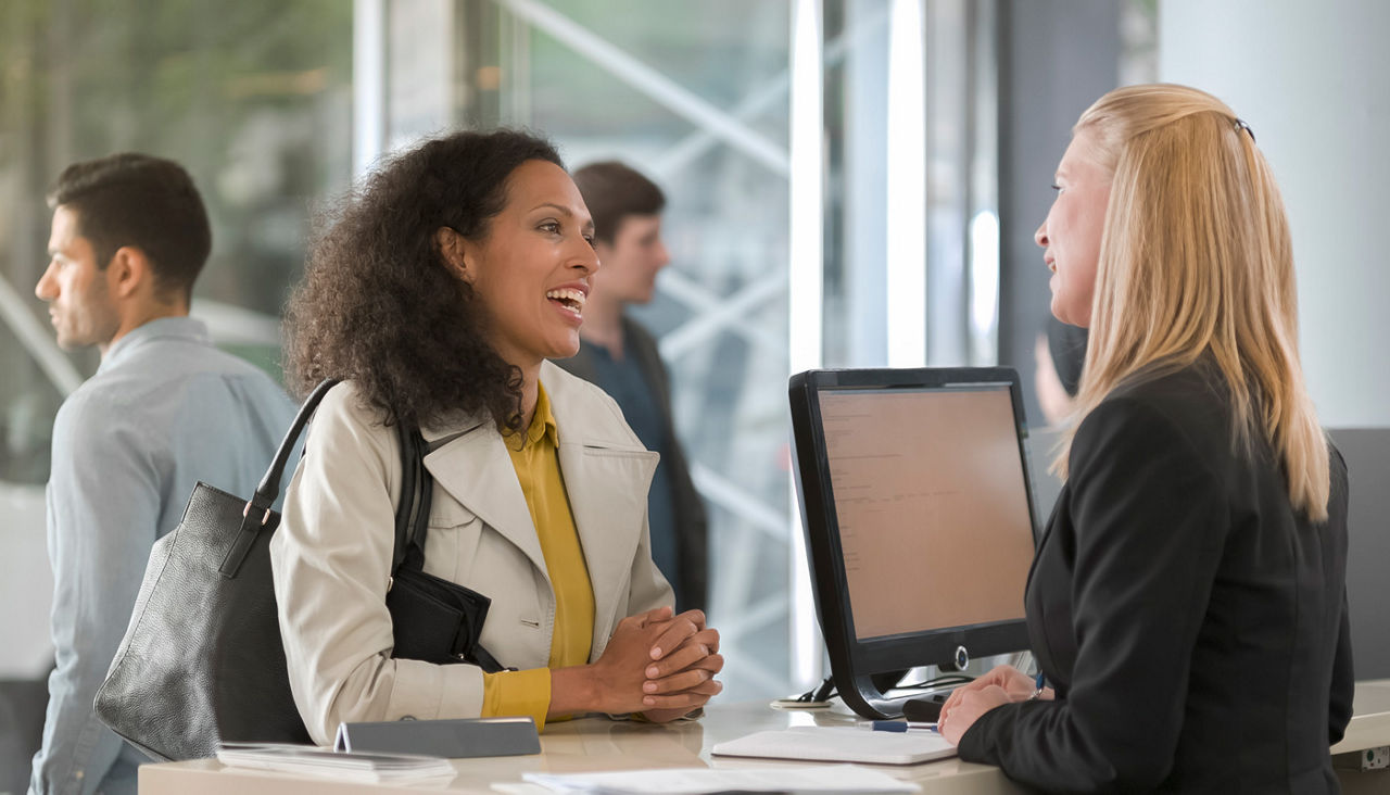 Woman asking rental agent for rental car type and female agent helping her