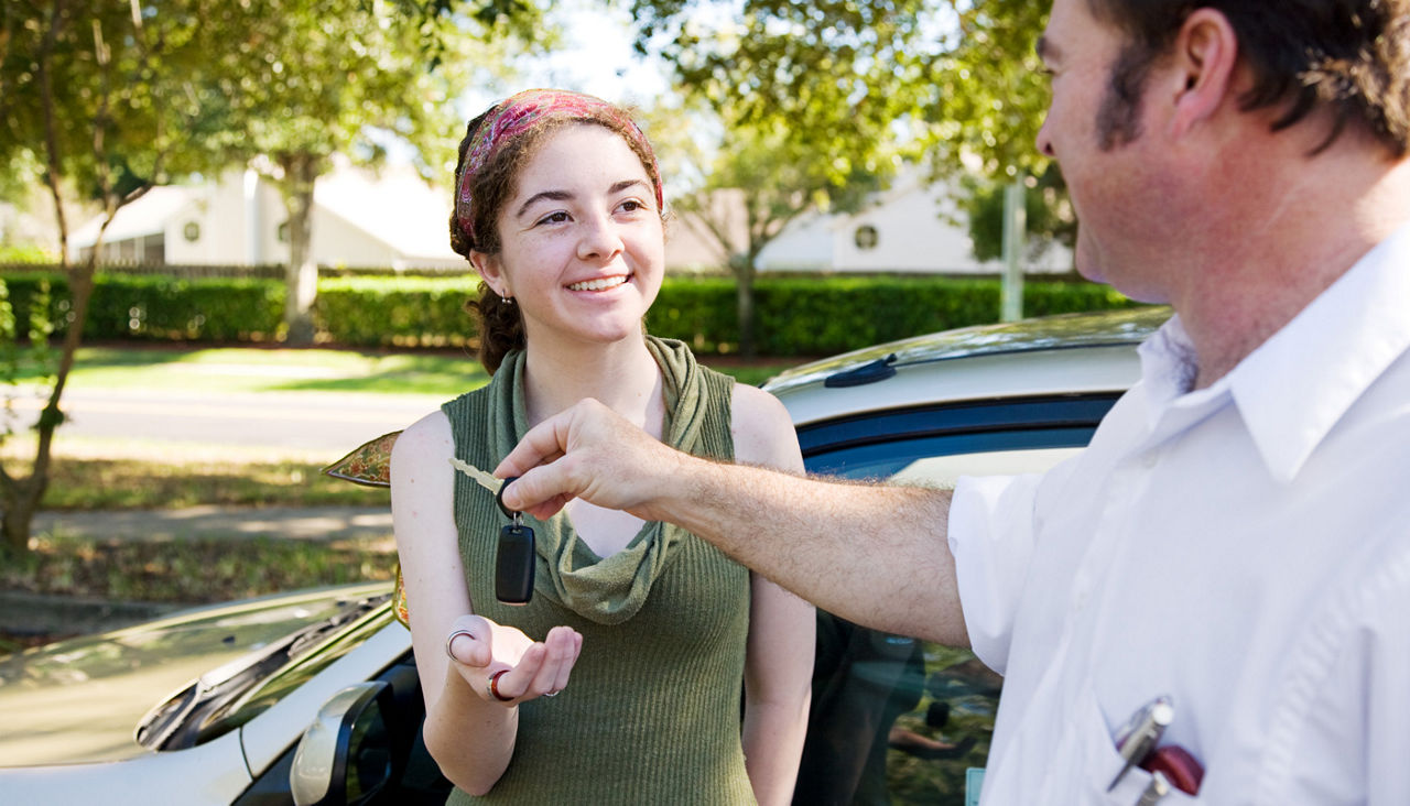 Father handing car keys to his young adult daughter