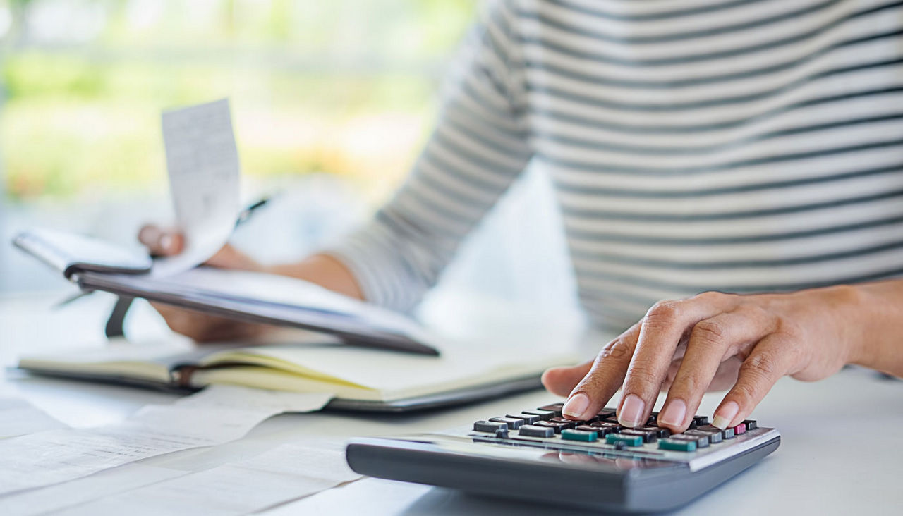 Woman with bills and calculator. Woman using calculator to calculate bills at the table in office.