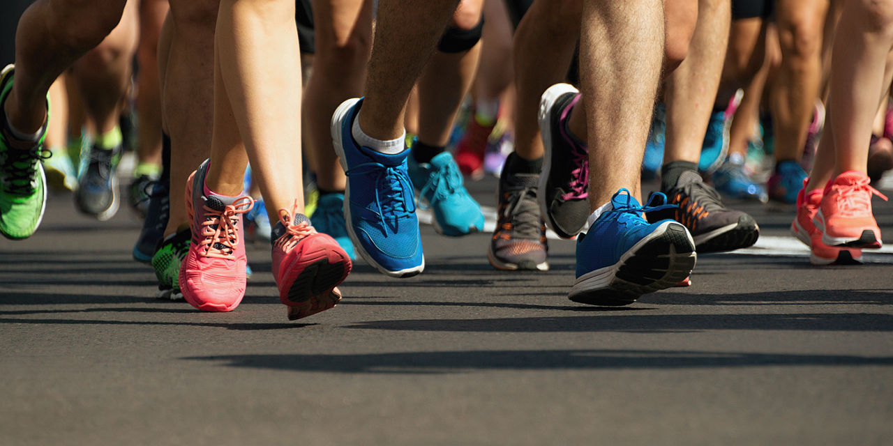 Marathon runners running on city road, detail on legs