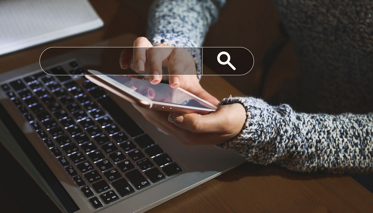Young woman with mobile phone and laptop using web search engine