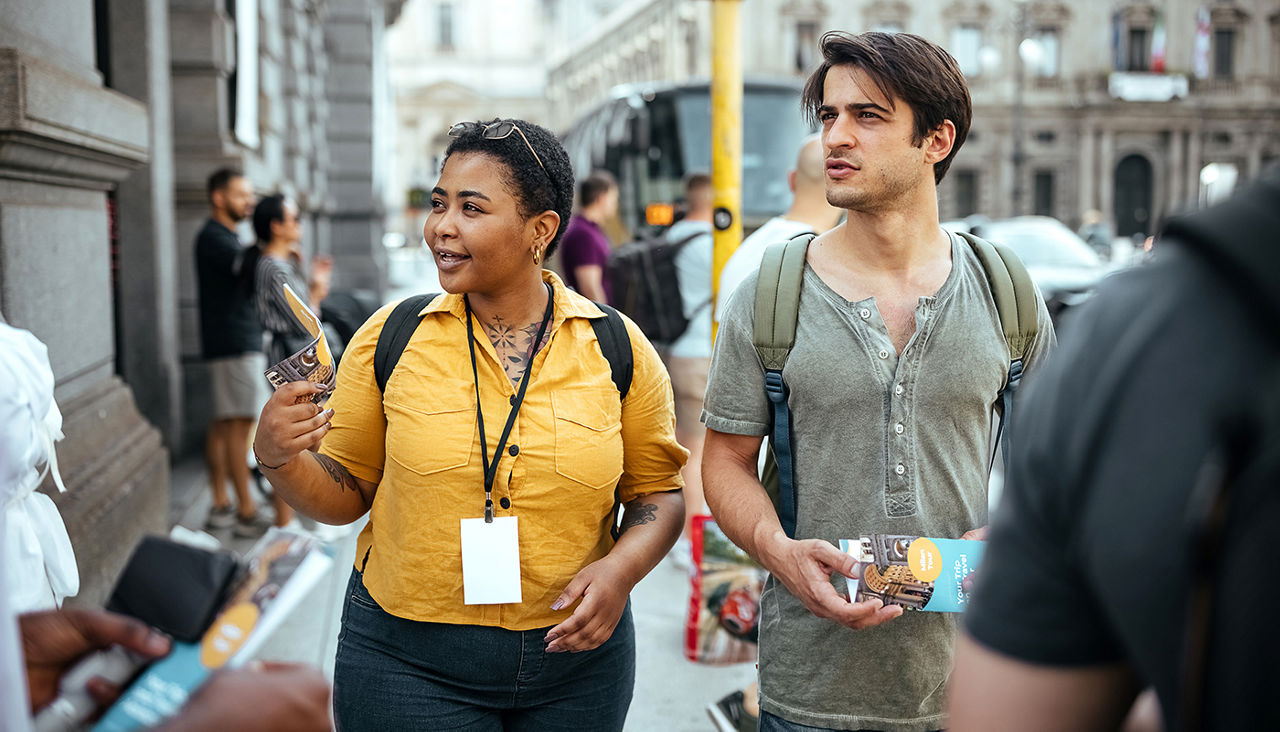 Travel guide talking to a group of tourists, explaining about downtown street