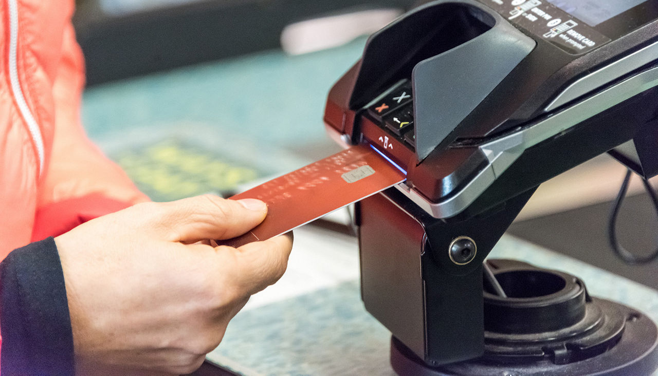 Closeup of hand inserting credit card into credit card chip reader