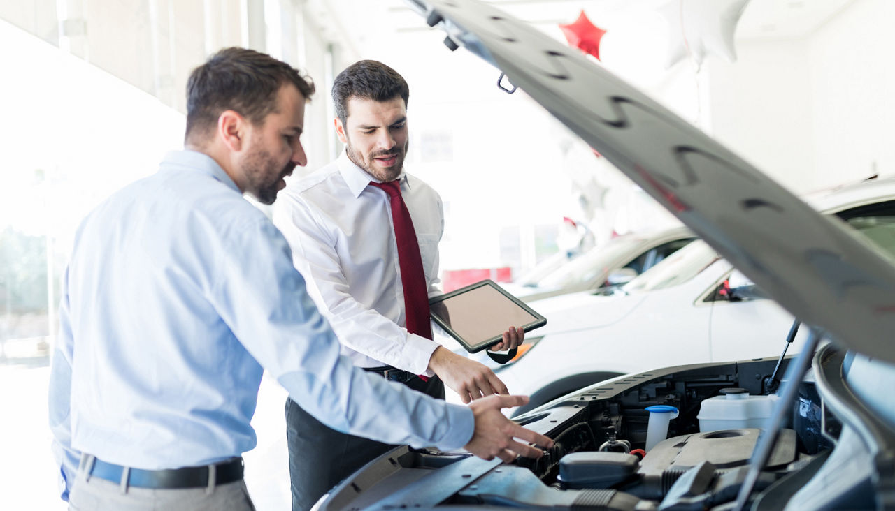 Car dealer showing customer car engine