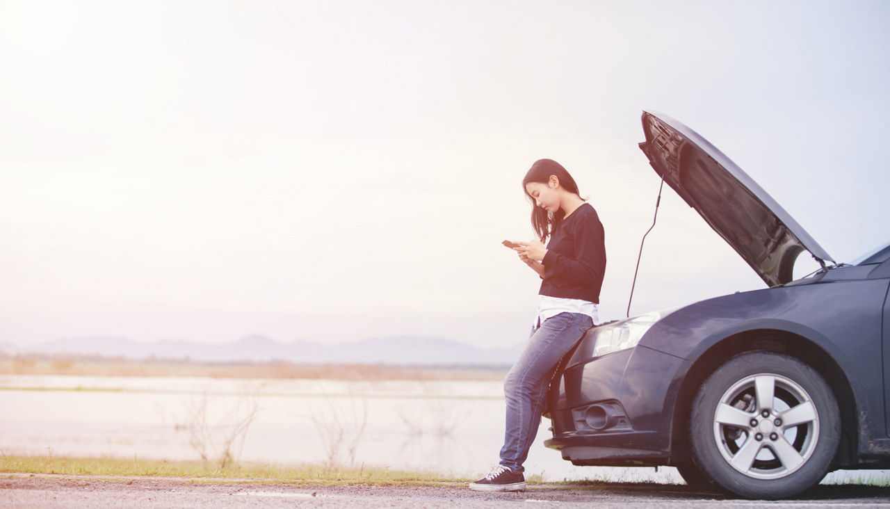 Woman is using a cell phone to call for help on roadside