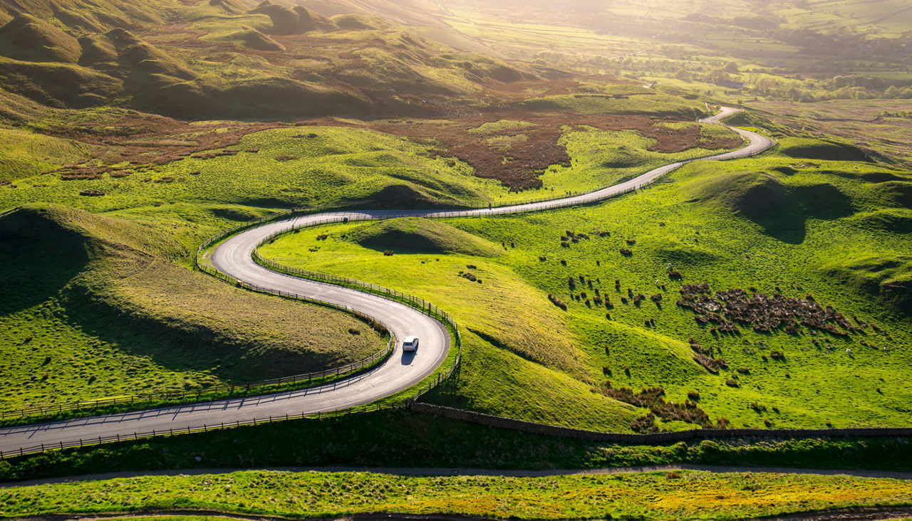 Car driving in the hills of England on a sunny evening