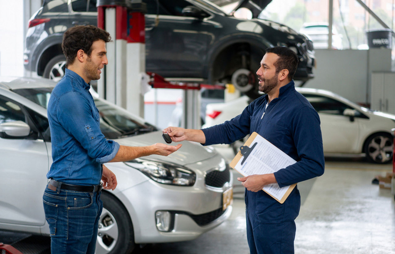 Man picking up his car at the auto repair shop and getting the keys from the mechanic