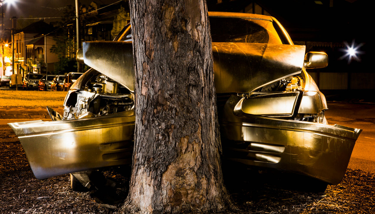 Car crashed on tree trunk at night