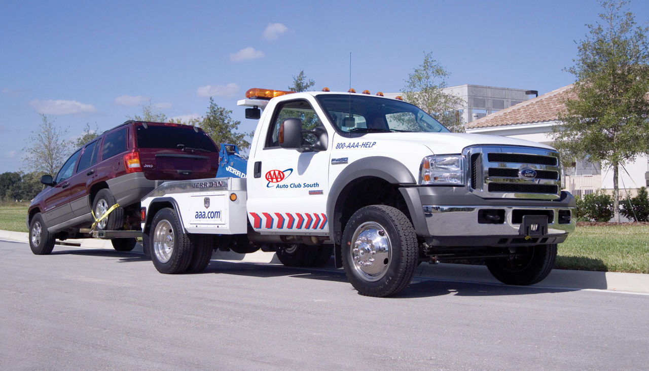 AAA tow truck towing an suv from a residential home.
