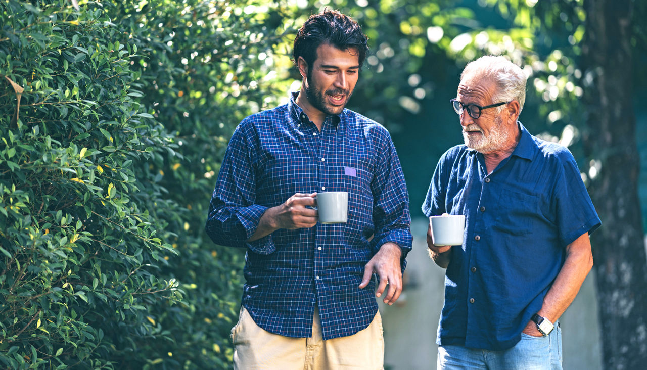 An adult son and senior father at home, talking