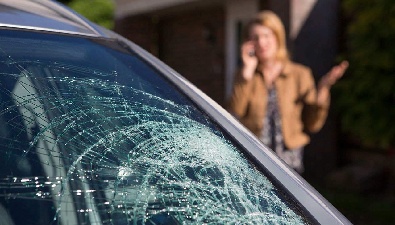 Woman Phoning For Help After Car Windshield Has Broken