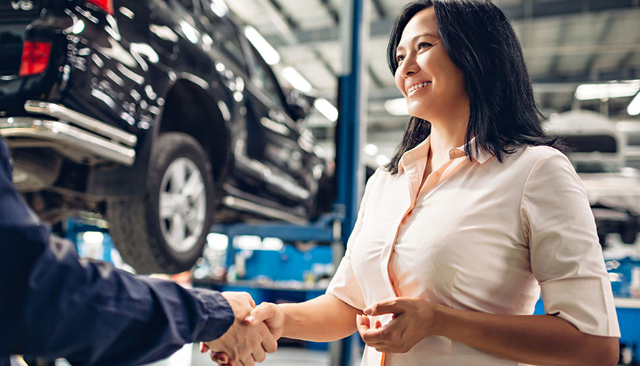 Car service center scene. The mechanic handshakes with the client