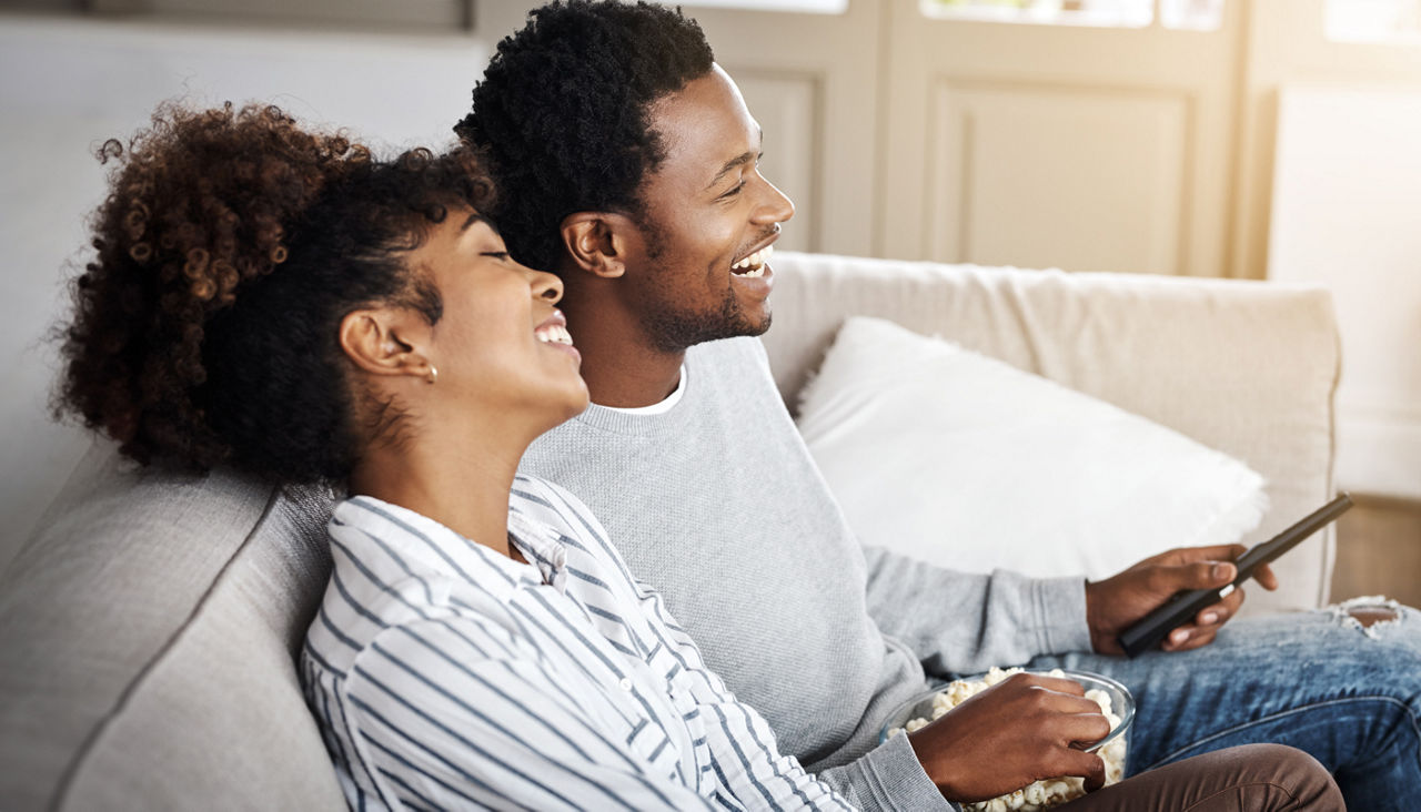 couple enjoying popcorn on the couch while watching TV