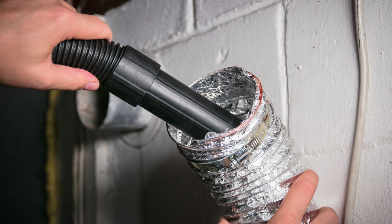 Vacuum cleaning a flexible aluminum dryer vent hose to remove lint and prevent fire hazard.